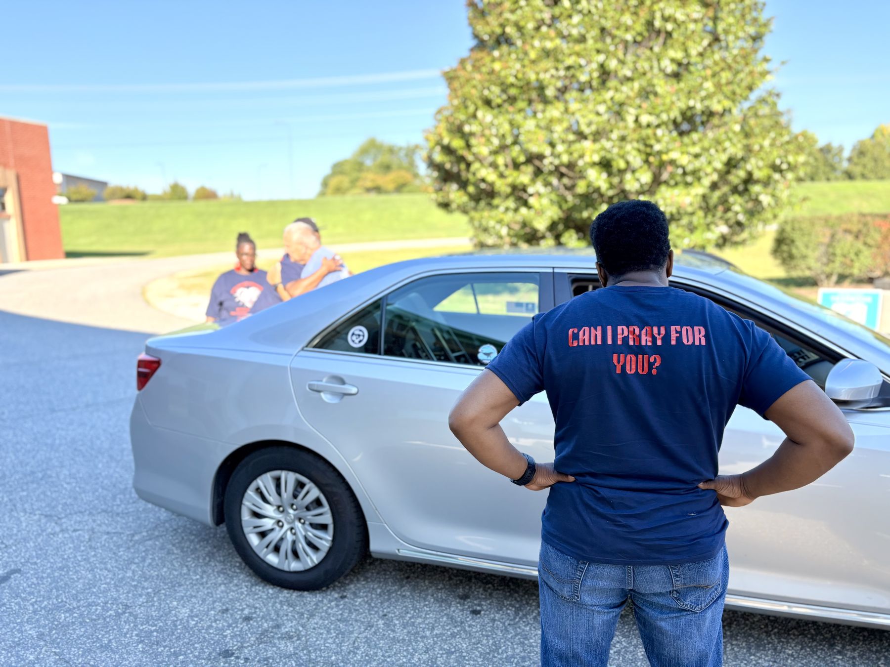 A volunteer wearing a shirt that reads Can I pray for you
