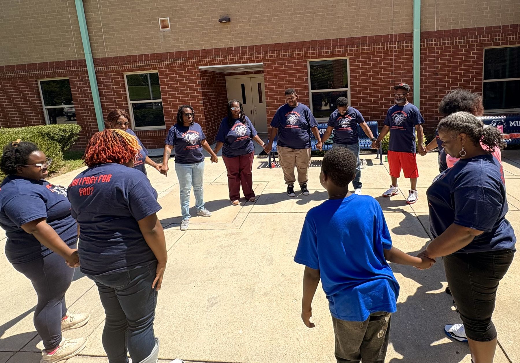Volunteers holding hands in a prayer circle